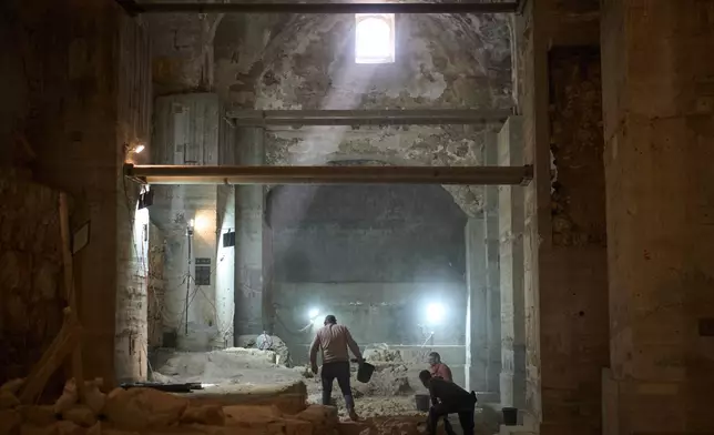 Workers from the Israel Antiquities Authority clean a section of an excavation site where, according to the institution, a city wall from the Hasmonean period, dating to the late 2nd century BCE, was uncovered under the Tower of David Citadel Museum, in the Old City of Jerusalem, Monday, Dec. 8, 2025. (AP Photo/Leo Correa)