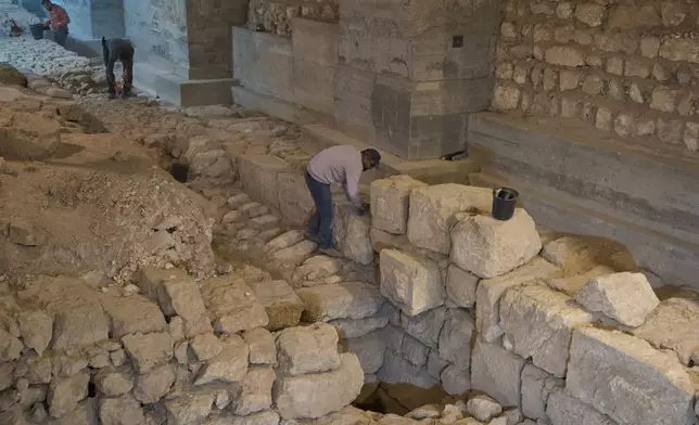 Workers from the Israel Antiquities Authority clean a section of an excavation site where, according to the institution, a city wall from the Hasmonean period, dating to the late 2nd century BCE, was uncovered under the Tower of David Citadel Museum, in the Old City of Jerusalem, Monday, Dec. 8, 2025. (AP Photo/Leo Correa)