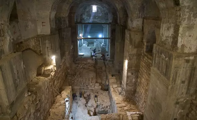 Workers from the Israel Antiquities Authority clean a section of an excavation site where, according to the institution, a city wall from the Hasmonean period, dating to the late 2nd century BCE, was uncovered under the Tower of David Citadel Museum, in the Old City of Jerusalem, Monday, Dec. 8, 2025. (AP Photo/Leo Correa)