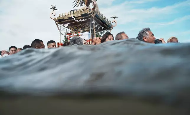 Participants carry a portable shrine, or mikoshi, into the sea during a purification rite at the annual Kurihama Sumiyoshi Shrine Festival at Kurihama, Yokosuka city, south of Tokyo Sunday, July 27, 2025. (AP Photo/Eugene Hoshiko, File)