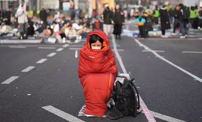 Jo Eun-jin, who stayed overnight on the street, waits for the start of a rally calling for impeached South Korean President Yoon Suk Yeol to step down, near the Constitutional Court in Seoul, South Korea, Friday, April 4, 2025. (AP Photo/Lee Jin-man, File)