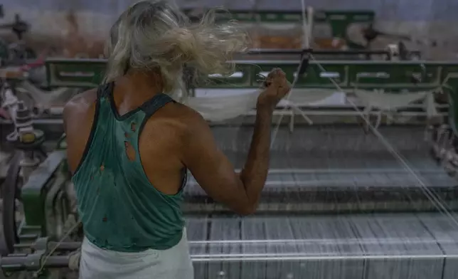 Abdul Sattar, 70, untangles a piece of thread from his hair as he operates a power weaving loom at a workshop in Bhiwandi, India, Feb. 25, 2025. (AP Photo/Rafiq Maqbool, File)