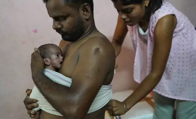 Antima Kumari helps her brother-in-law Sikandar Chaudhary hold his son close with the Kangaroo Mother Care (KMC), a skin-to-skin contact to promote bonding and well-being, at home in Gurugram, a satellite city of New Delhi, India, on Aug. 8, 2025. (AP Photo/Manish Swarup, File)