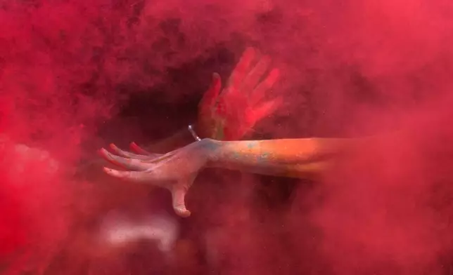 A girl throws colored powder on her friend as they celebrate Holi, the Hindu festival of colors, in Mumbai, India, Friday, March 14, 2025. (AP Photo/Rafiq Maqbool, File)
