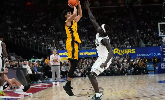 Oakland guard Brett White II, left, shoots against Michigan State guard Kur Teng during the first half of an NCAA college basketball game, Saturday, Dec. 20, 2025, in Detroit. (AP Photo/Ryan Sun)