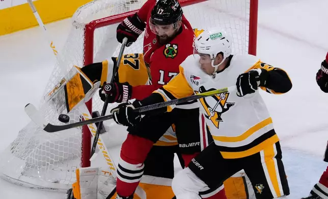 Chicago Blackhawks left wing Nick Foligno (17) battles for the puck against Pittsburgh Penguins goaltender Arturs Silovs, left, and defenseman Jack St. Ivany, right, during the first period of an NHL hockey game in Chicago, Sunday, Dec. 28, 2025. (AP Photo/Nam Y. Huh)
