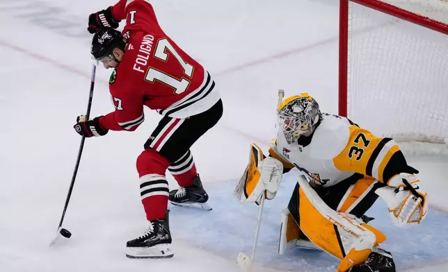 Chicago Blackhawks left wing Nick Foligno, left, scores against Pittsburgh Penguins goaltender Arturs Silovs during the second period of an NHL hockey game in Chicago, Sunday, Dec. 28, 2025. (AP Photo/Nam Y. Huh)