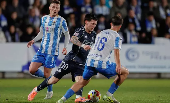 Real Madrid's Franco Mastantuono, center, duels for the balls with Talavera's Iaiah Jeronimo during the Copa del Rey soccer match between Talavera and Real Madrid, in Talavera de la Reina, Spain, Wednesday, Dec. 17, 2025. (AP Photo/M. Berengui)