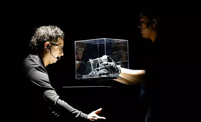 A worker moves a microphone used by Charlie Kirk at Utah Valley University on the day he was fatally shot during Turning Point USA's AmericaFest 2025, Thursday, Dec. 18, 2025, in Phoenix. (AP Photo/Jon Cherry)