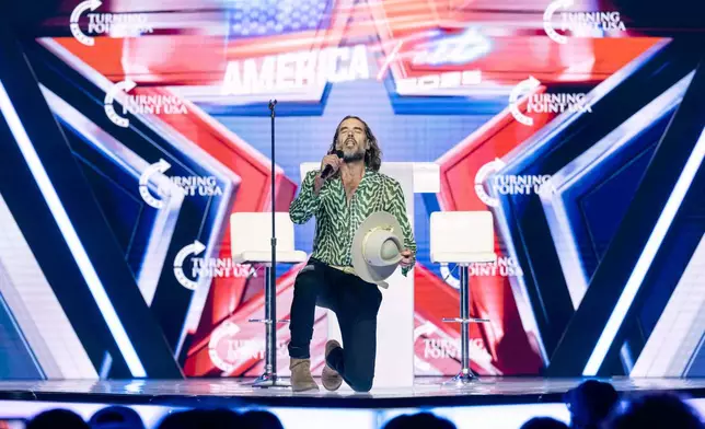 Russell Brand speaks during Turning Point USA's AmericaFest 2025, Thursday, Dec. 18, 2025, in Phoenix. (AP Photo/Jon Cherry)