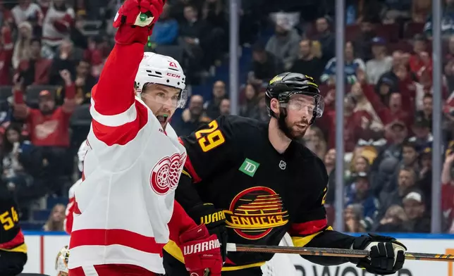 Detroit Red Wings' James van Riemsdyk (21) celebrates his goal as Vancouver Canucks' Marcus Pettersson (29) skates away during first period NHL hockey action in Vancouver, B.C., Monday, Dec. 8, 2025. (Ethan Cairns/The Canadian Press via AP)