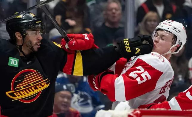 Vancouver Canucks' Evander Kane (91) punches Detroit Red Wings' Jacob Bernard-Docker (25) during the third period of an NHL hockey game in Vancouver, B.C., Monday, Dec. 8, 2025. (Ethan Cairns/The Canadian Press via AP)