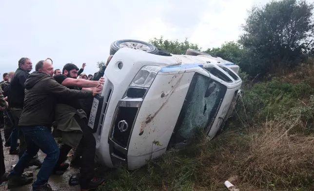 Farmers overturn a police vehicle during clashes with officers blocking their march to Chania's airport on Crete, Greece, Monday, Dec. 8, 2025, amid protests over delayed EU farm subsidies. (AP Photo/Giannis Angelakis)