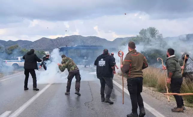 Farmers throw stones at police during clashes with officers blocking their march to Chania's airport on Crete, Greece, Monday, Dec. 8, 2025, amid protests over delayed EU farm subsidies. (AP Photo/Giannis Angelakis)
