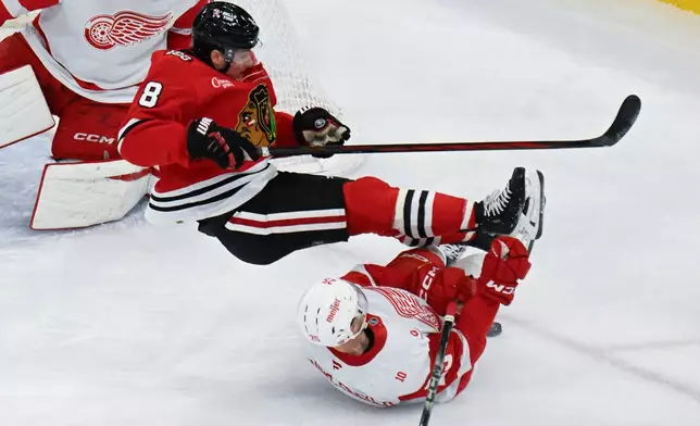 Chicago Blackhawks center Ryan Donato (8) is tripped by Detroit Red Wings defenseman Jacob Bernard-Docker (25) during the second period of an NHL hockey game, Saturday, Dec. 13, 2025, in Chicago. (AP Photo/Matt Marton)