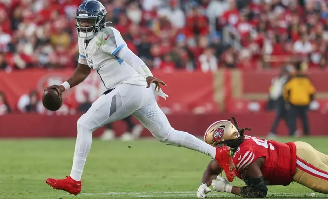 Tennessee Titans quarterback Cam Ward (1) escapes pressure from San Francisco 49ers defensive tackle Kalia Davis, right, during the second half of an NFL football game, Sunday, Dec. 14, 2025, in Santa Clara, Calif. (AP Photo/Jed Jacobsohn)