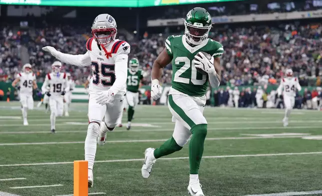 New York Jets running back Breece Hall (20) runs for a touchdown against New England Patriots cornerback Miles Battle (35) during the second half of an NFL football game, Sunday, Dec. 28, 2025, in East Rutherford, N.J. (AP Photo/Adam Hunger)