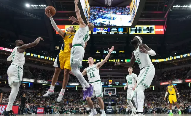 Indiana Pacers guard Andrew Nembhard (2) goes up to shoot around Boston Celtics guard Derrick White (9) during the first half of an NBA basketball game in Indianapolis, Friday, Dec. 26, 2025. (AP Photo/AJ Mast)