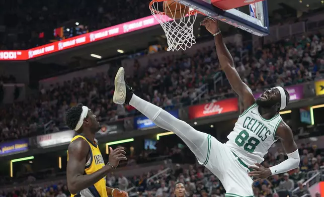 Boston Celtics center Neemias Queta, right, dunks in front of Indiana Pacers forward Pascal Siakam, left, during the first half of an NBA basketball game in Indianapolis, Friday, Dec. 26, 2025. (AP Photo/AJ Mast)
