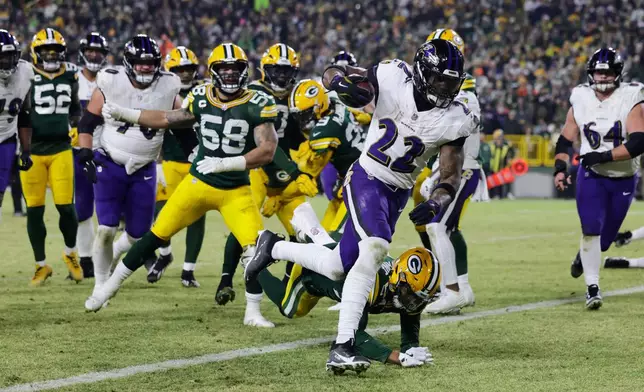 Baltimore Ravens running back Derrick Henry (22) scores a touchdown past Green Bay Packers cornerback Carrington Valentine (24) during the first half of an NFL football game, Saturday, Dec. 27, 2025, in Green Bay, Wis. (AP Photo/Matt Ludtke)