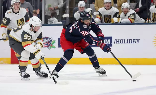 Columbus Blue Jackets right wing Kirill Marchenko (86) controls the puck as Vegas Golden Knights right wing Mitch Marner (93) plays defense during the second period of an NHL hockey game, Saturday, Dec. 13, 2025, in Columbus, Ohio. (AP Photo/Joe Maiorana)