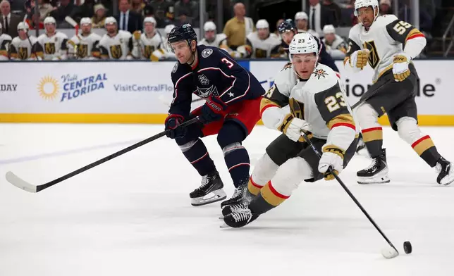Vegas Golden Knights left wing Cole Reinhardt (23) controls the puck as Columbus Blue Jackets center Charlie Coyle (3) skates past during the first period of an NHL hockey game, Saturday, Dec. 13, 2025, in Columbus, Ohio. (AP Photo/Joe Maiorana)