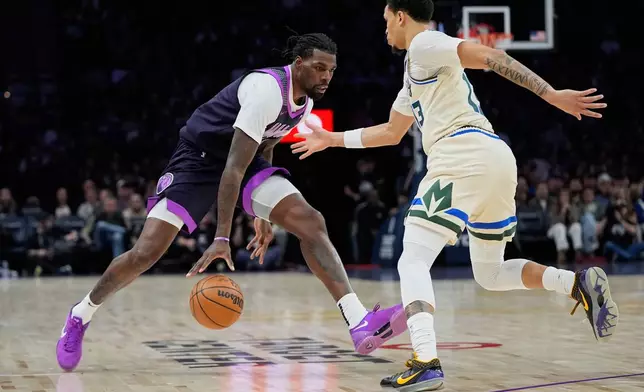 Minnesota Timberwolves center Naz Reid, left, works toward the basket as Milwaukee Bucks guard Ryan Rollins defends during the first half of an NBA basketball game, Sunday, Dec. 21, 2025, in Minneapolis. (AP Photo/Abbie Parr)