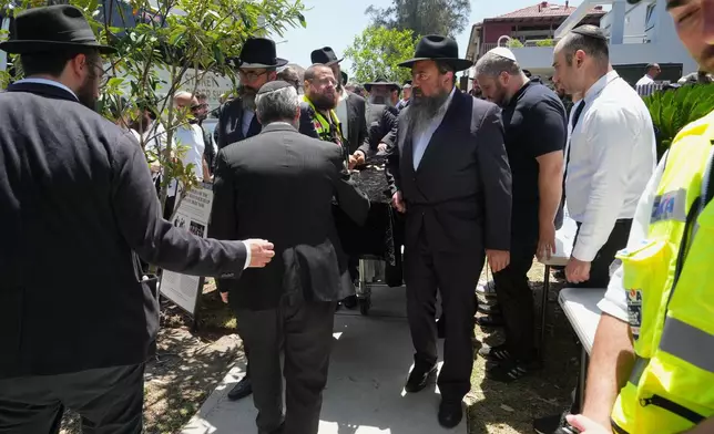The coffin of Rabbi Eli Schlanger, a victim in the Bondi Beach mass shooting, is escorted out of a synagogue after his funeral service in Bondi on Wednesday, Dec. 17, 2025, in Sydney, Australia. (AP Photo/Mark Baker, Pool)