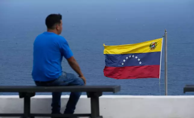 A man looks out at the sea in the city of La Guaira, Venezuela, where the nation's flag flies, Wednesday, Dec. 17, 2025. (AP Photo/Ariana Cubillos)