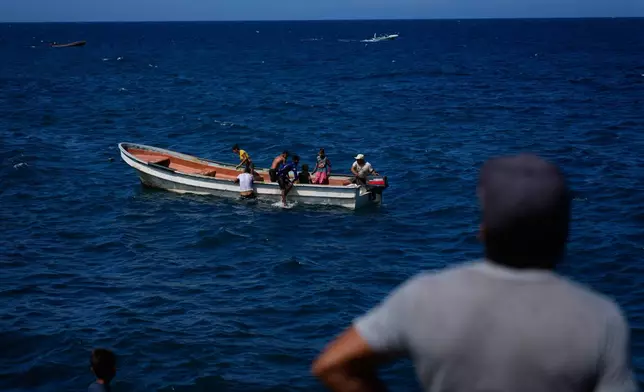People ride a boat along the coast in Macuto, Venezuela, Wednesday, Dec. 17, 2025. (AP Photo/Ariana Cubillos)