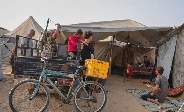 Yassin Marouf, 23, second from right, who lost his left foot and suffered a severe injury to his right leg after Israeli shelling in May, sits on a mattress in a tent surrounded by family and neighbors in Zawaida, central Gaza, Thursday, Nov. 6, 2025. (AP Photo/Abdel Kareem Hana)