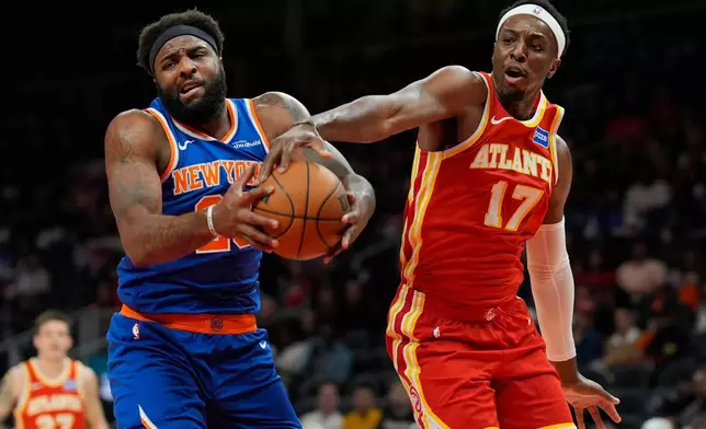 New York Knicks center Karl-Anthony Towns (32) and Atlanta Hawks forward Onyeka Okongwu (17) vie for a loose ball during the first half of an NBA basketball game, Saturday, Dec. 27, 2025, in Atlanta. (AP Photo/Mike Stewart)