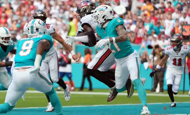 Tampa Bay Buccaneers wide receiver Chris Godwin Jr. (14) makes a catch for a touchdown against Miami Dolphins safety Ashtyn Davis (21) during the first half of an NFL football game Sunday, Dec. 28, 2025, in Miami Gardens, Fla. (AP Photo/Rebecca Blackwell)