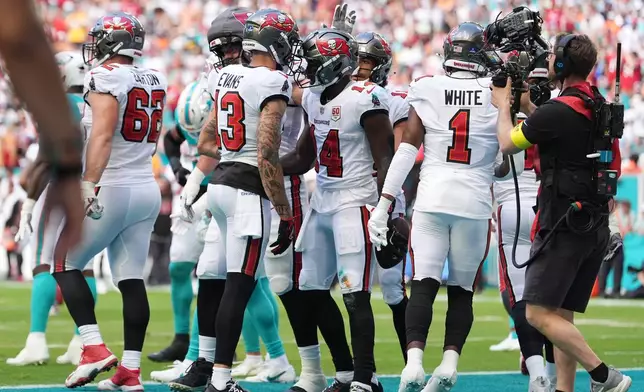 Tampa Bay Buccaneers wide receiver Chris Godwin Jr. (14) celebrates with wide receiver Mike Evans (13) after scoring a touchdown against the Miami Dolphins during the first half of an NFL football game Sunday, Dec. 28, 2025, in Miami Gardens, Fla. (AP Photo/Rebecca Blackwell)