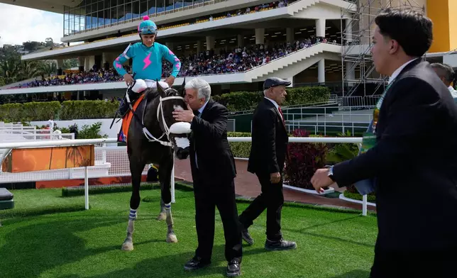 An owner kisses Latina Parts during the 56th Jockey Challenge at the Rinconada racetrack in Caracas, Venezuela, Sunday, Dec. 14, 2025. (AP Photo/Arian Cubillos)