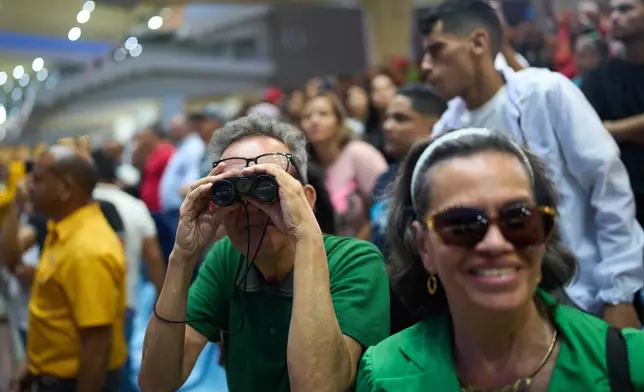 Spectators watch horse racing during the 56th Jockey Challenge at the Rinconada racetrack in Caracas, Venezuela, Sunday, Dec. 14, 2025. (AP Photo/Arian Cubillos)