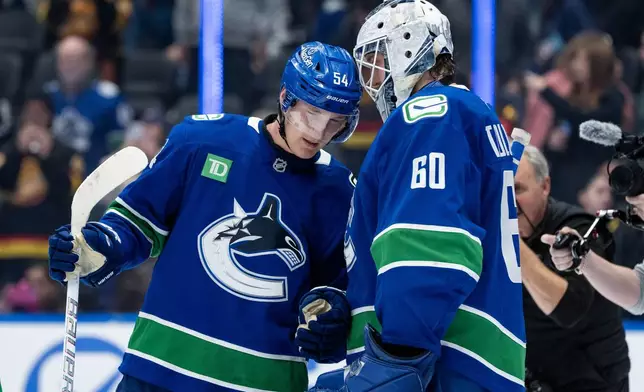 Vancouver Canucks Aatu Raty (54) and goaltender Nikita Tolopilo (60) celebrate after defeating the Minnesota Wild after third period NHL hockey game action in Vancouver, British Columbia, Saturday, Dec. 6, 2025. (Ethan Cairns/The Canadian Press via AP)