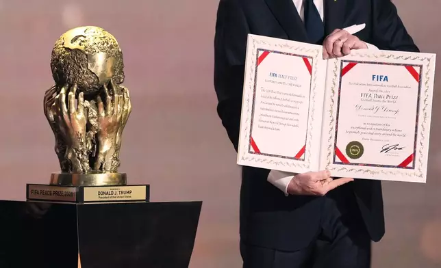 FIFA President Gianni Infantino presents President Donald Trump with the FIFA Peace Prize during the draw for the 2026 soccer World Cup at the Kennedy Center in Washington, Friday, Dec. 5, 2025. (AP Photo/Stephanie Scarbrough, Pool)