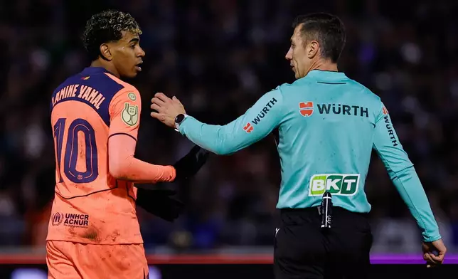 Barcelona's Lamine Yamal, left, talks with the referee during the Copa del Rey soccer match between Guadalajara and Barcelona in Guadalajara, Spain, Tuesday, Dec. 16, 2025. (AP Photo/Rudy Garcia)