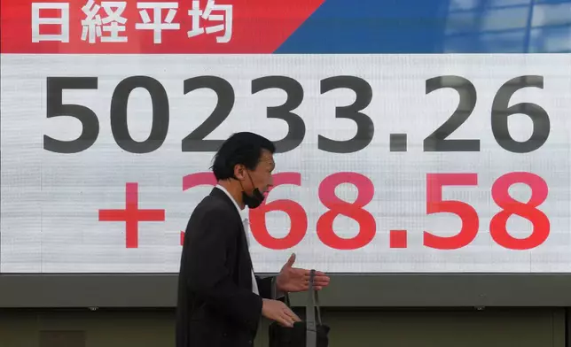 A person walks in front of an electronic stock board showing Japan's Nikkei index at a securities firm Thursday, Dec. 4, 2025, in Tokyo. (AP Photo/Eugene Hoshiko)