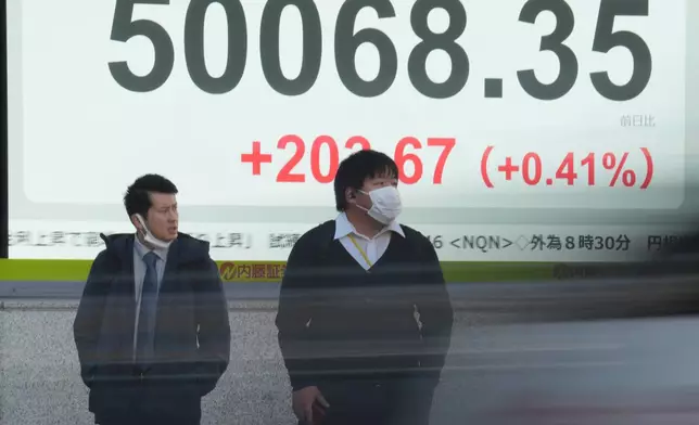 People stand in front of an electronic stock board showing Japan's Nikkei index at a securities firm Thursday, Dec. 4, 2025, in Tokyo. (AP Photo/Eugene Hoshiko)