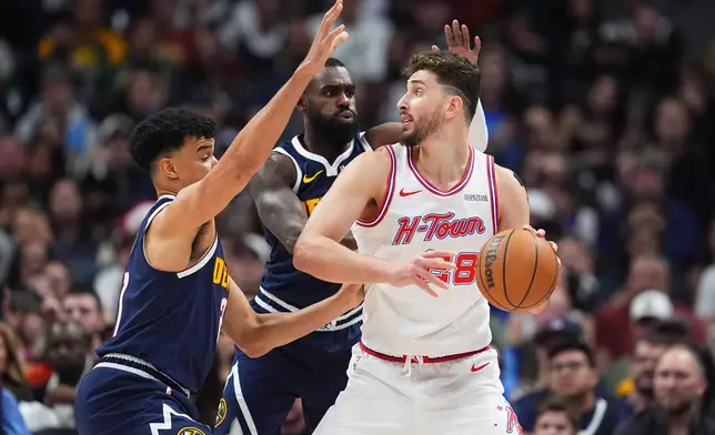 Houston Rockets center Alperen Sengun, right, looks to pass the ball as Denver Nuggets forward Spencer Jones, left, and guard Tim Hardaway Jr., center, defend in the first half of an NBA basketball game Monday, Dec. 15, 2025, in Denver. (AP Photo/David Zalubowski)