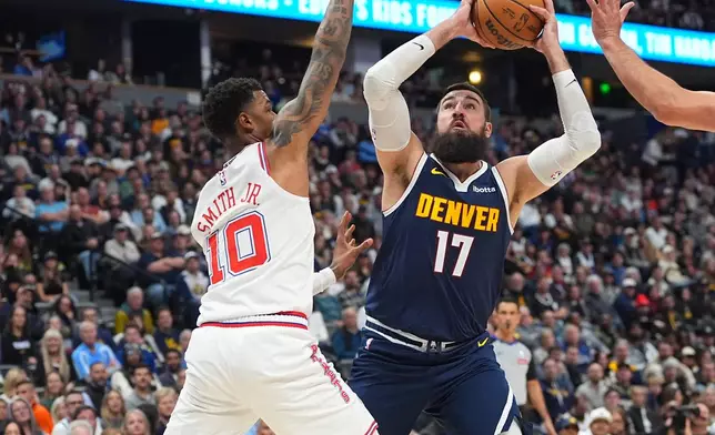 Denver Nuggets center Jonas Valančiūnas (17) goes up for a basket as Houston Rockets forward Jabari Smith Jr. (10) defends in the first half of an NBA basketball game Monday, Dec. 15, 2025, in Denver. (AP Photo/David Zalubowski)