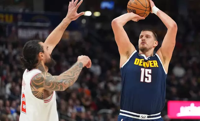 Denver Nuggets center Nikola Jokić, right, looks to shoot a basket over Houston Rockets center Steven Adams, left, in the first half of an NBA basketball game Monday, Dec. 15, 2025, in Denver. (AP Photo/David Zalubowski)