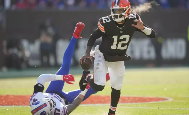 Cleveland Browns quarterback Shedeur Sanders eludes the tackle of Buffalo Bills defensive end AJ Epenesa (57)during the first half of an NFL football game in Cleveland, Sunday, Dec. 21, 2025. (AP Photo/Sue Ogrocki)