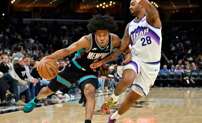 Memphis Grizzlies forward Jaylen Wells, left, drives against Utah Jazz forward Brice Sensabaugh (28) in the second half of an NBA basketball game Friday, Dec. 12, 2025, in Memphis, Tenn. (AP Photo/Brandon Dill)