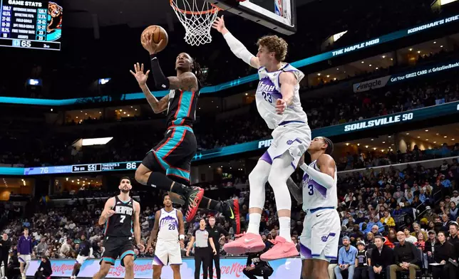 Memphis Grizzlies guard Ja Morant, top left, shoots ahead of Utah Jazz forward Lauri Markkanen (23) in the second half of an NBA basketball game Friday, Dec. 12, 2025, in Memphis, Tenn. (AP Photo/Brandon Dill)