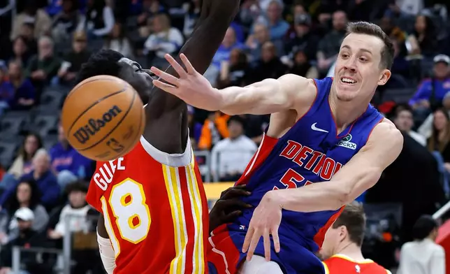 Detroit Pistons forward Duncan Robinson, right, passes the ball past Atlanta Hawks forward Mouhamed Gueye, left, during the second half of an NBA basketball game Friday, Dec. 12, 2025, in Detroit. (AP Photo/Duane Burleson)