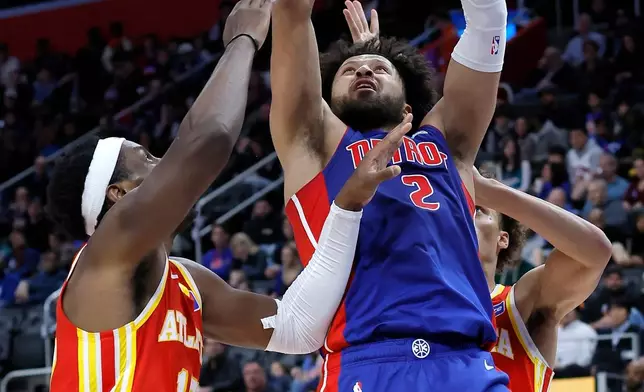 Detroit Pistons guard Cade Cunningham (2) goes to the basket against Atlanta Hawks forward Onyeka Okongwu, left, and guard Dyson Daniels, back right, during the second half of an NBA basketball game Friday, Dec. 12, 2025, in Detroit. (AP Photo/Duane Burleson)