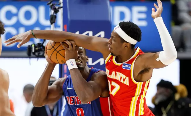 Detroit Pistons center Jalen Duren (0) tries to get a shot off against Atlanta Hawks forward Onyeka Okongwu (17) during the first half of an NBA basketball game Friday, Dec. 12, 2025, in Detroit. (AP Photo/Duane Burleson)